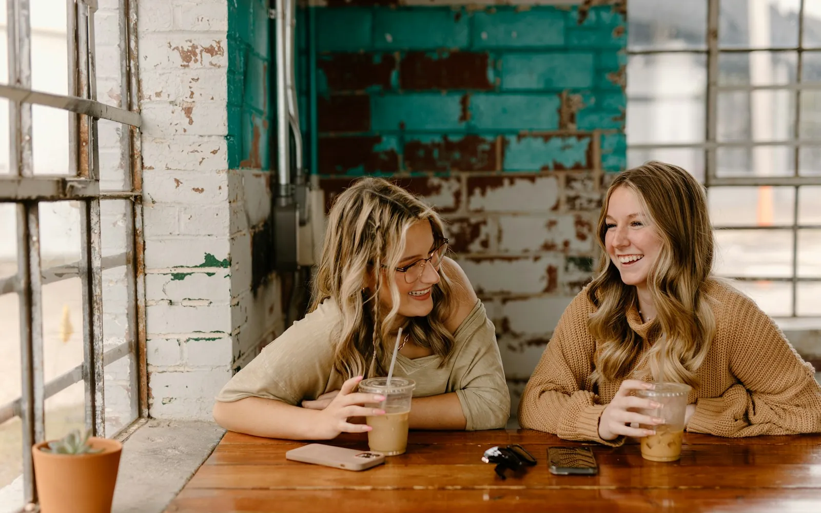 Two friends laughing together over coffee at a cafe table