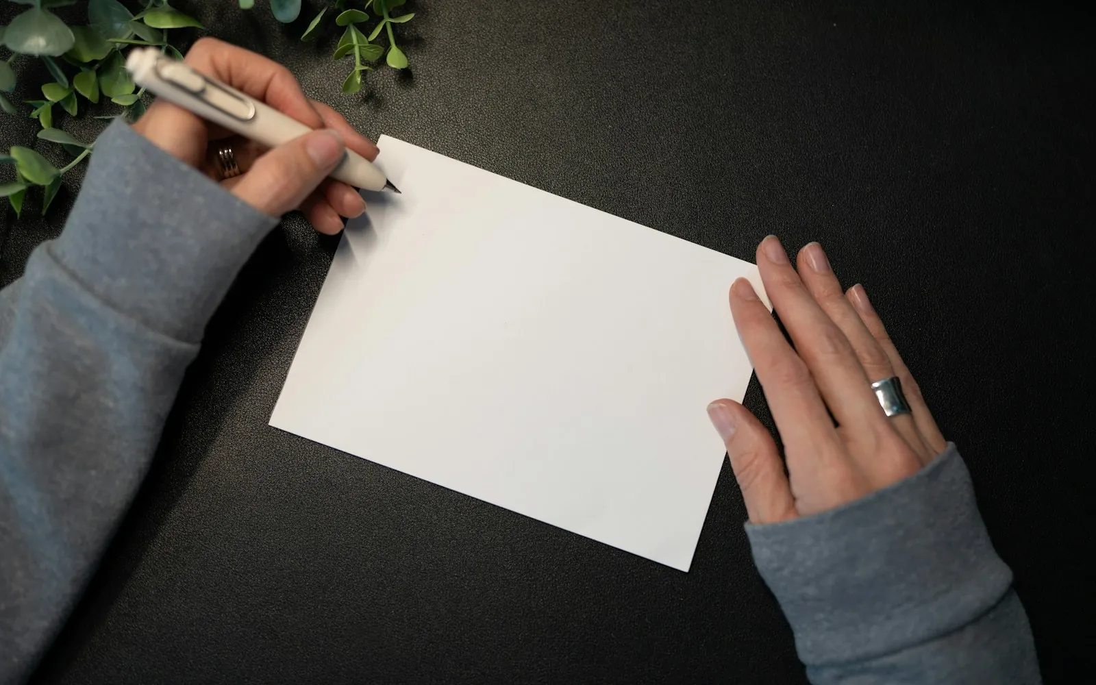 Hands writing a thank-you card with a pen